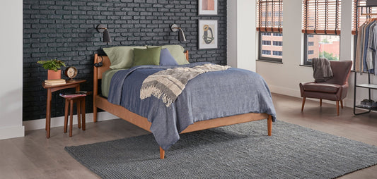 Bed with gray blanket and green accent pillows in a modern industrial bedroom