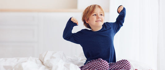 young boy stretching in bed