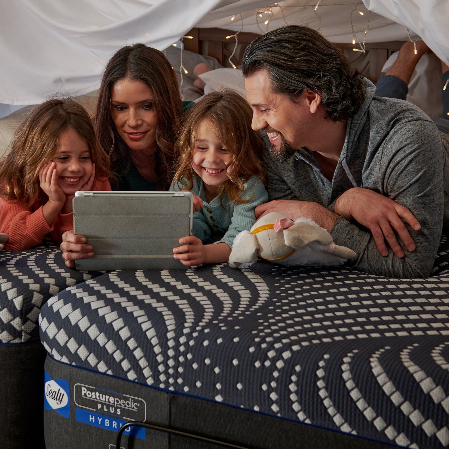 Family Using Tablet On Sealy High Point Soft Hybrid Mattress In Bedroom
