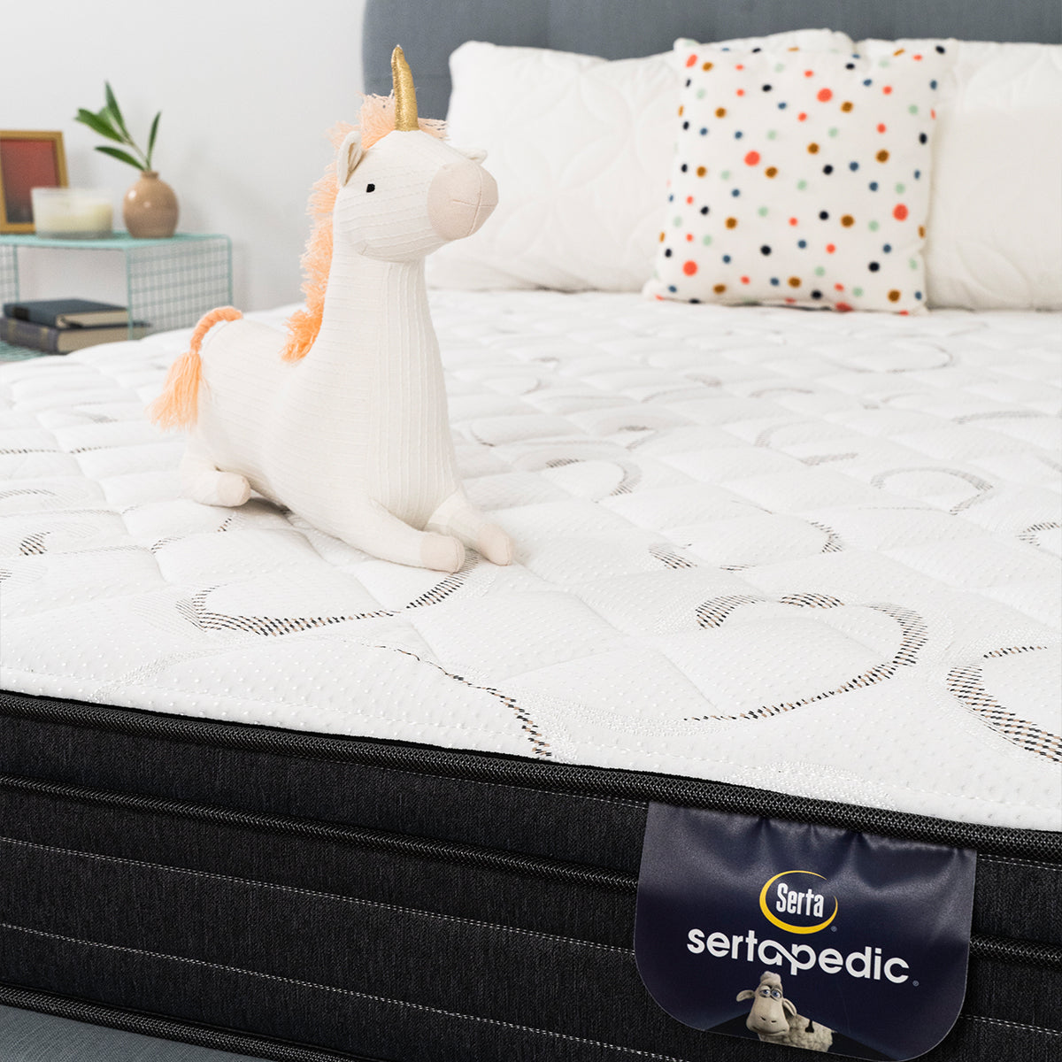 Sertapedic Elkridge Euro Top Mattress by Serta Closeup Shot With Unicorn Plushies. Product Fabric Detail And Lbael.