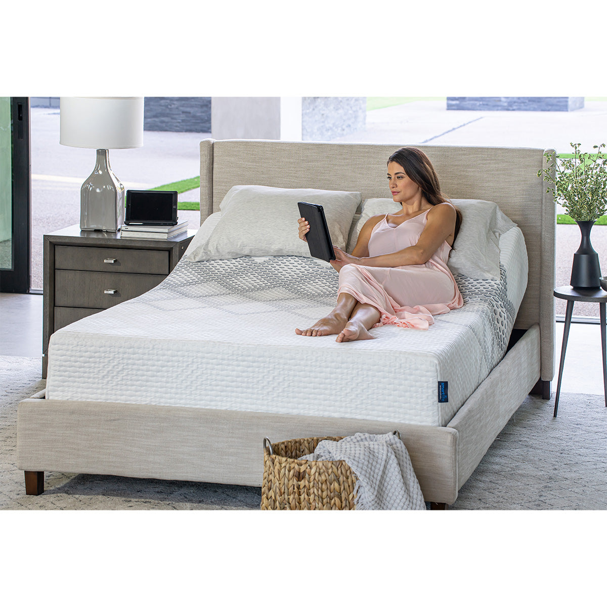 Woman using a smart device to adjust the settings on a SmartLife Lily Medium Mattress on an adjustable base