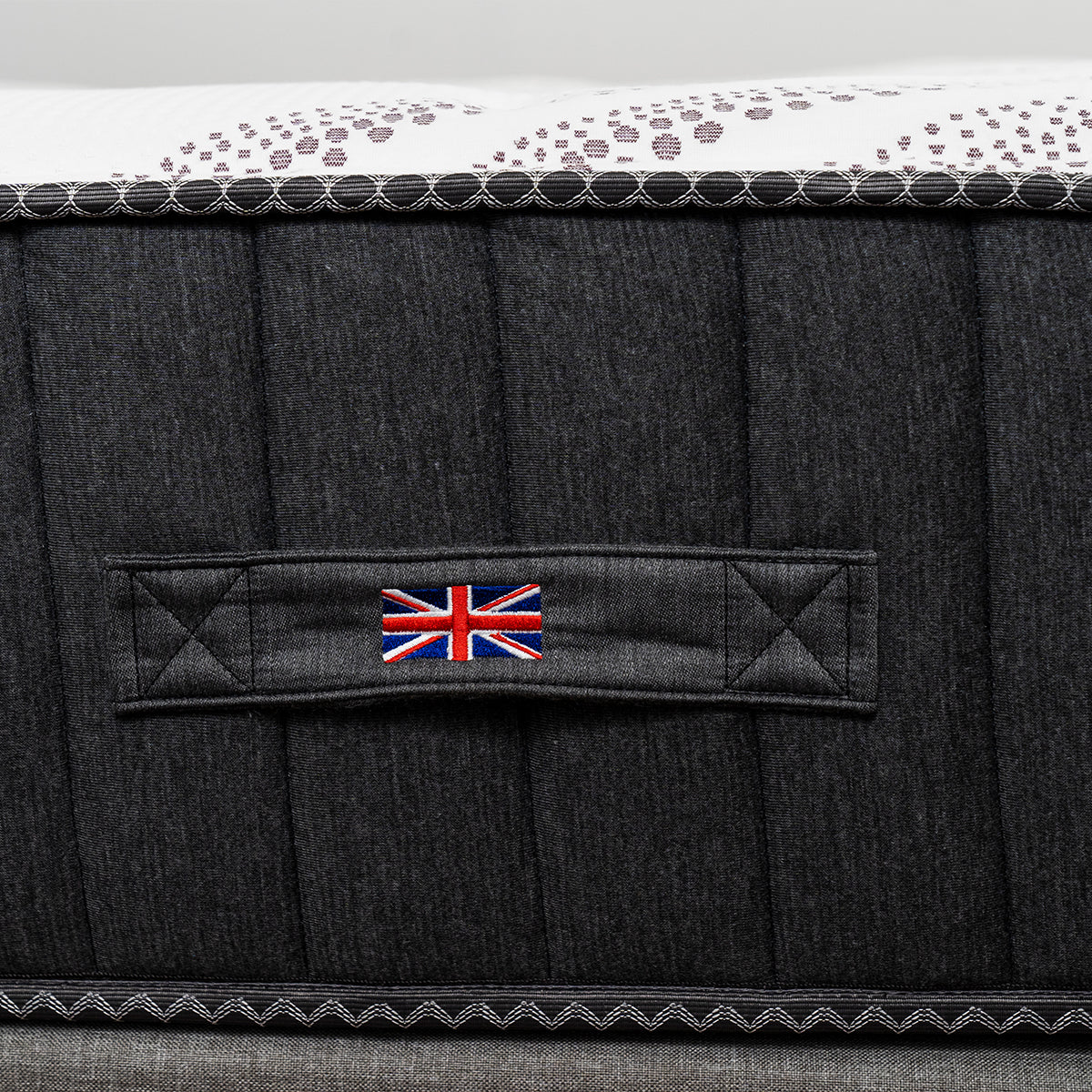 Spink and Co Padworth Firm mattress side detailing showcasing the carrying handle with Union Jack flag and mattress cover fabric.