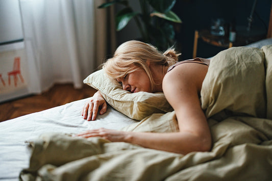 Woman sleeping on her stomach in bed with her head on a pillow