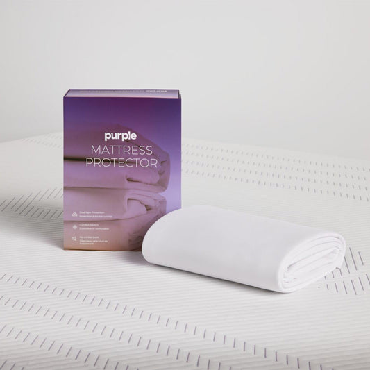 Purple Deep Pocket Mattress Protector Folded On A Bed Next To The Packaging