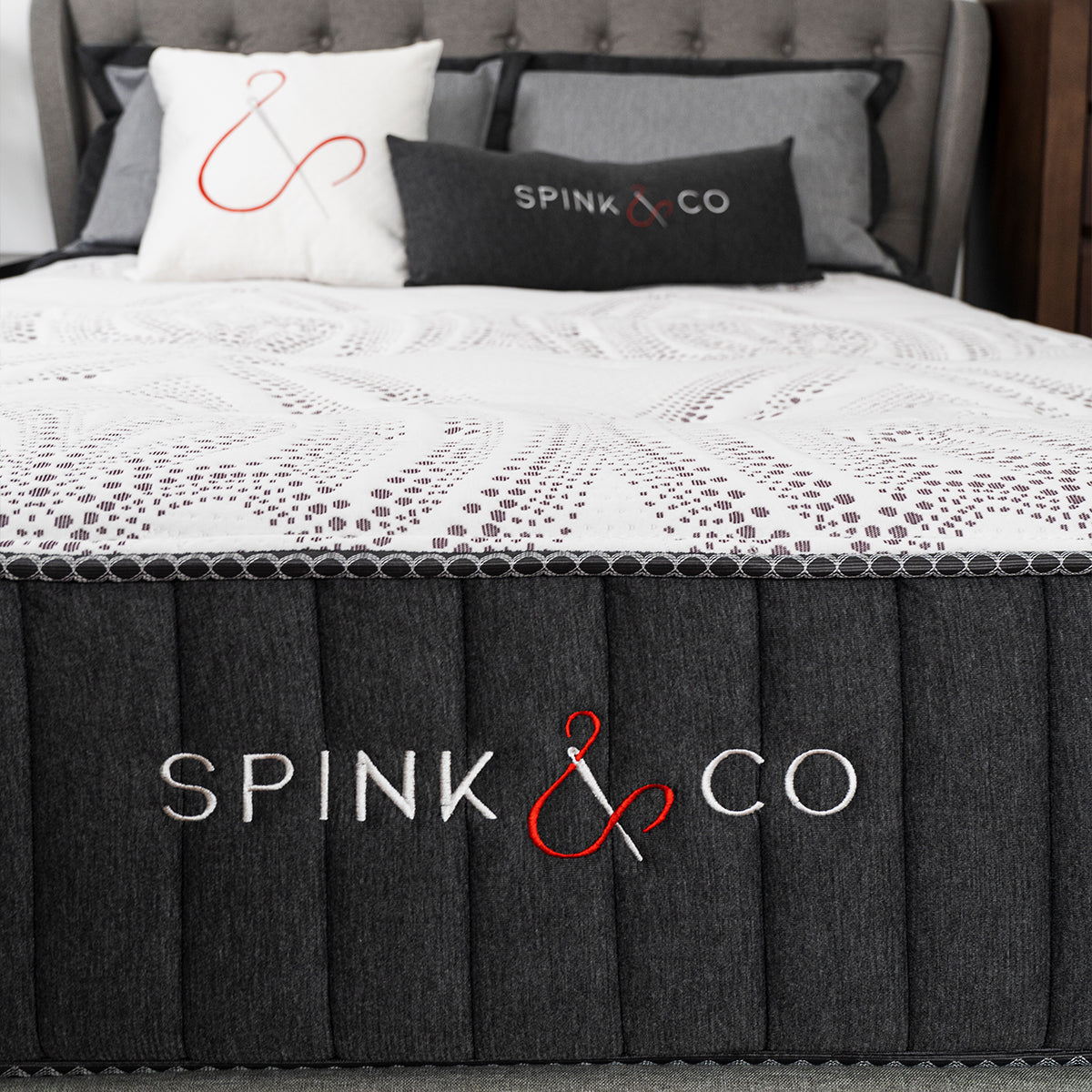 Spink & Co Padworth Firm mattress closeup of the front of the mattress, showing logo hand stitched, in clean modern bedroom with Spink & Co accessory throw pillows